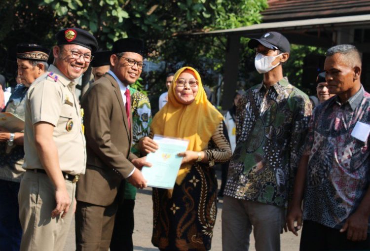 Indra Gunawan (kiri) bersama Imam Budi Hartono menyerahkan sertifikat PTSL kepada warga, perwakilan Pemkot Depok dan PUPR di sela-sela upacara Hantaru 2023, di halaman Kantor Pertanahan Kota Depok. (Foto : BPN Kota Depok)