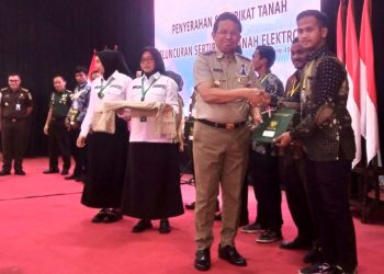 Agustin Iterson Samosir menyerahkan sertipikat tanah kepada warga. (Foto : Rolan - sinarjambi.com)