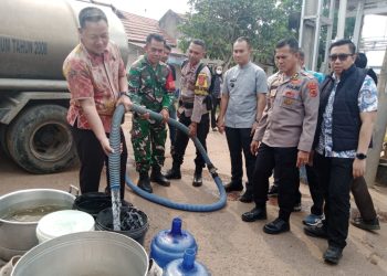AKBP Agung Basuki (kiri) menyalurkan langsung air bersih kepada warga. (Foto : Rolan - sinarjambi.com)