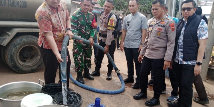 AKBP Agung Basuki (kiri) menyalurkan langsung air bersih kepada warga. (Foto : Rolan - sinarjambi.com)
