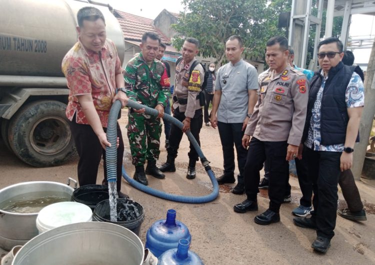 AKBP Agung Basuki (kiri) menyalurkan langsung air bersih kepada warga. (Foto : Rolan - sinarjambi.com)