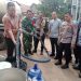 AKBP Agung Basuki (kiri) menyalurkan langsung air bersih kepada warga. (Foto : Rolan - sinarjambi.com)